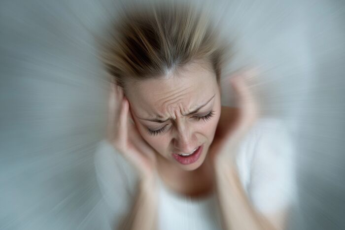 A woman experiencing extreme illness and sickness, clutching her head in distress and pain.