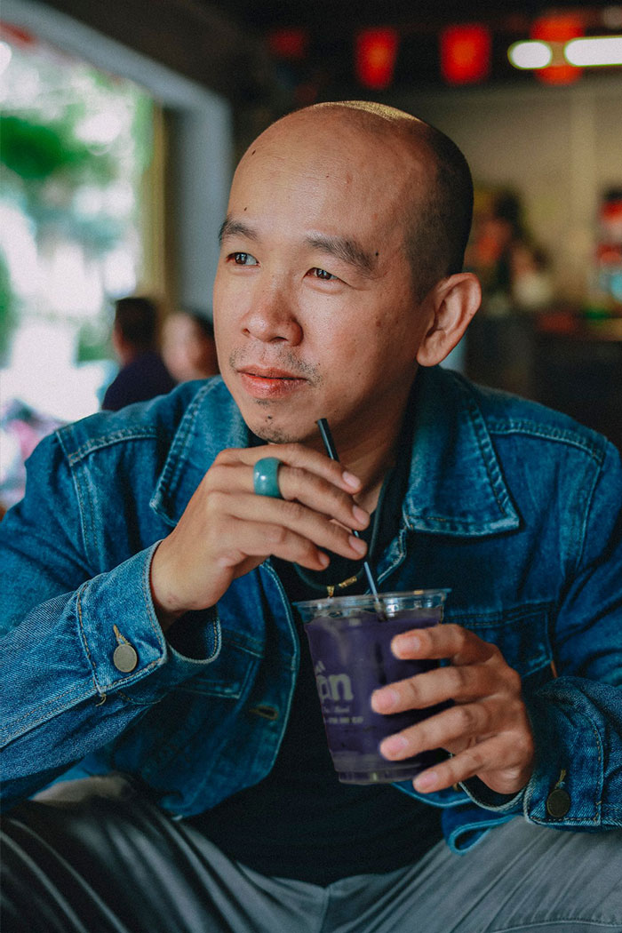 A patient in a denim jacket drinking a purple beverage through a straw, relating to patient wellbeing.