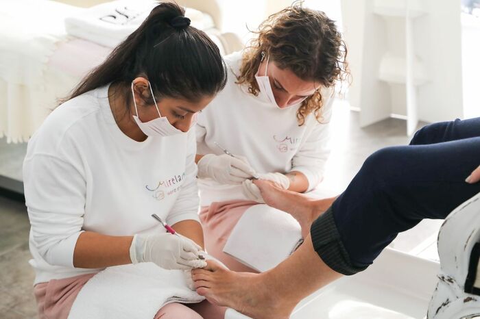 Two medical professionals giving a patient a pedicure, illustrating a medical education scenario.