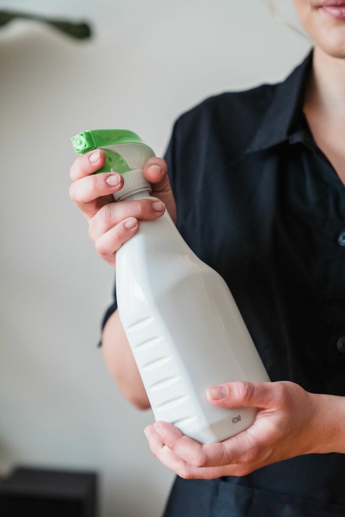 A person holds a cleaning spray bottle, highlighting a potential dumb patient interaction with chemicals.
