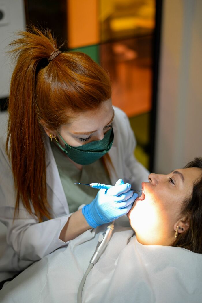 A dentist examining a patient's teeth, highlighting a patient seeking professional medical education and care.