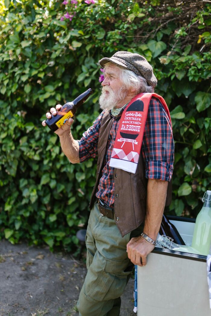 An older patient with a beard drinking beer outdoors, illustrating aspects of patient health.