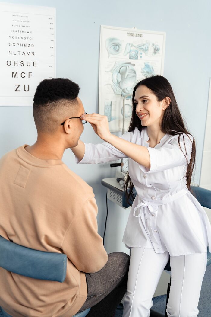 A female medical professional adjusting a patient's glasses during an eye exam, highlighting medical education.