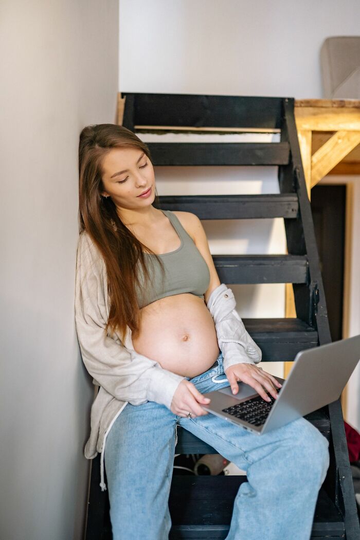 A pregnant woman works on a laptop, a common patient scenario.