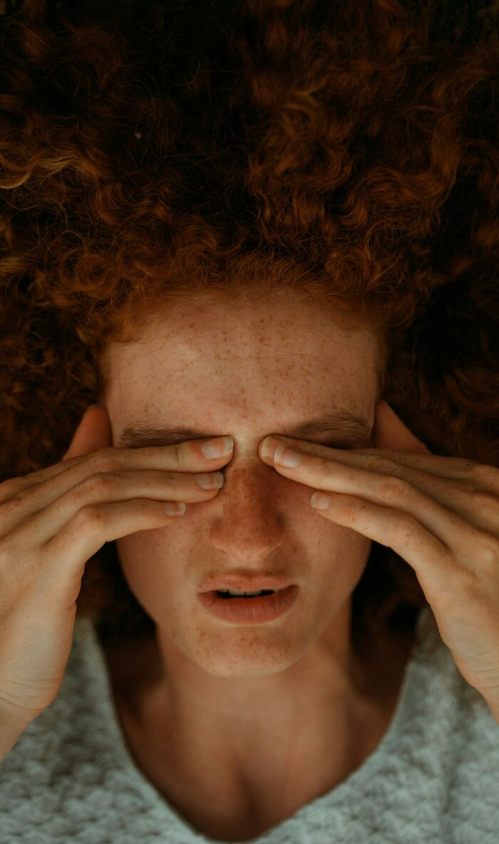 Close-up of a person with red hair covering their eyes, depicting patients ignoring health warnings.