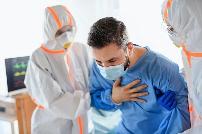 Medical personnel assisting a patient in a hospital gown and mask, highlighting patient support and medical education.