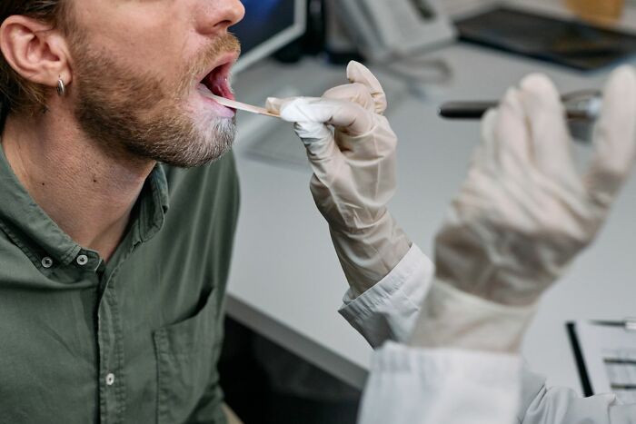 A doctor examining a patient's throat with a tongue depressor, emphasizing medical education practices.