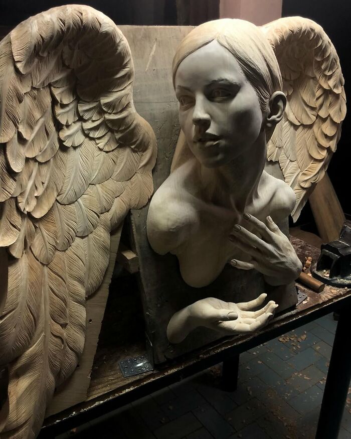 An angel with detailed wings carved from blocks of wood by a Polish artist.