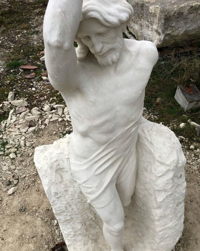 A Polish artist creates a white marble sculpture of a bearded man with lifelike muscles.