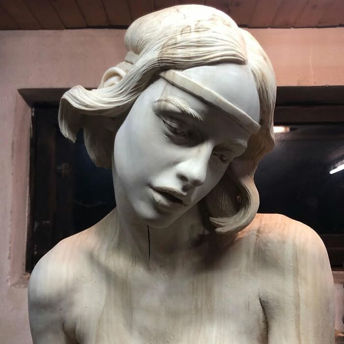 A lifelike sculpture of a woman’s head, carved from a block of wood by a Polish artist.