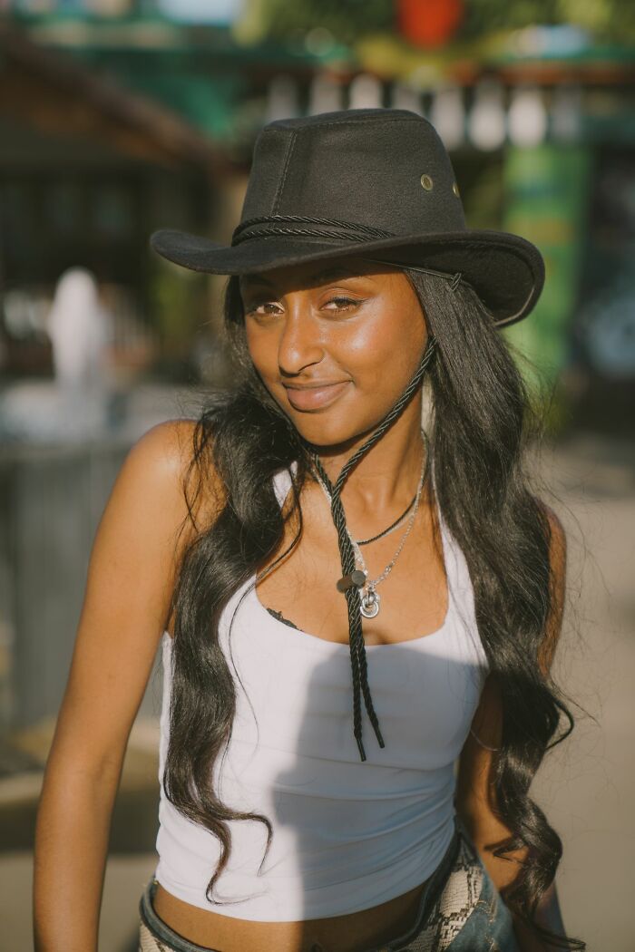 Confident woman wearing a cowboy hat smiling, showcasing personalities that make men lose interest in a woman