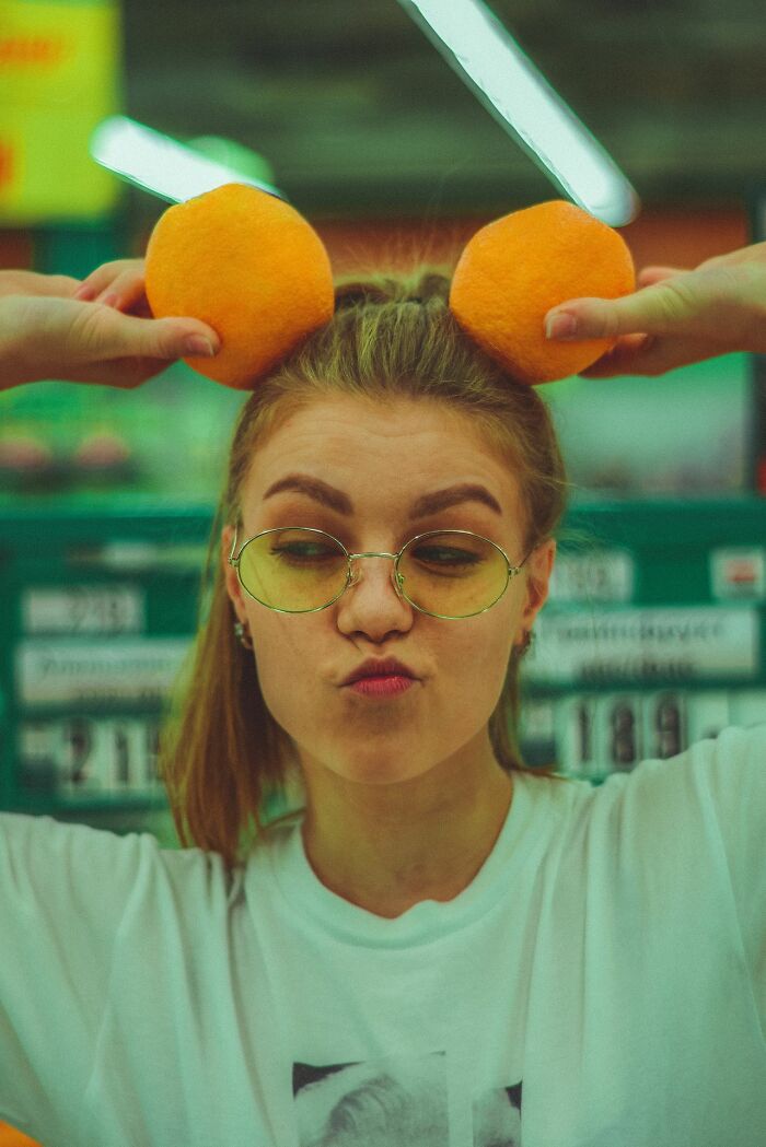 A goofy woman holding oranges like ears, a playful act that can make men lose interest