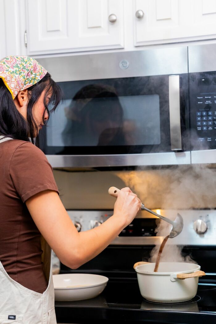A woman cooking at the stove, reflecting on small things that cause men lose interest in a woman instantly