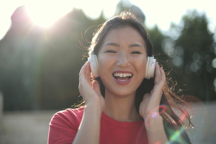 A smiling woman wearing headphones, reflecting traits that cause men to lose interest in a woman.