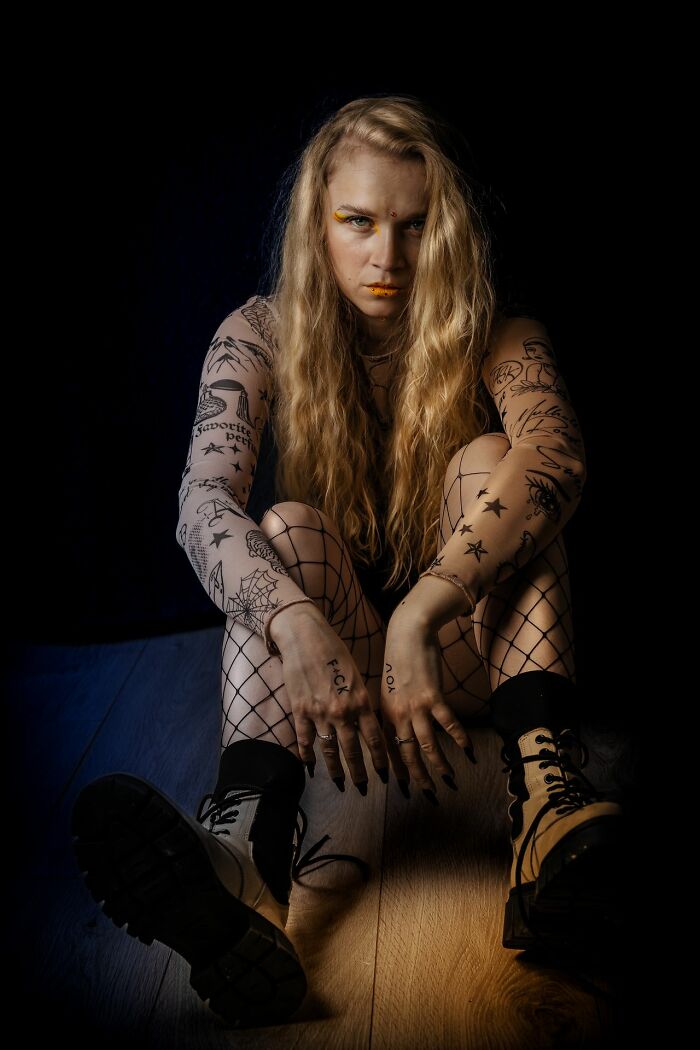 A tattooed woman sitting on the floor, reflecting traits that cause men lose interest in a woman