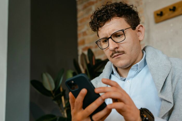 A young man looking at his phone, depicting how men lose interest in a woman.