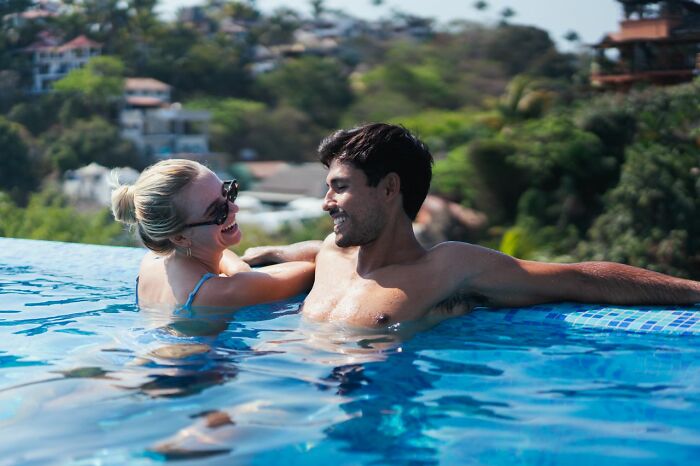 A man in a pool smiling at a woman, highlighting how men lose interest in a woman.