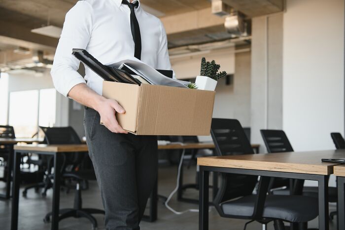 An office worker carrying a box of personal belongings after someone else's mistake led to a job change.
