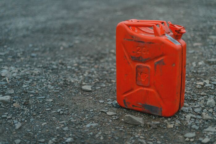 A bright red gas can resting on a gravel surface, evoking childhood beliefs about fuel.