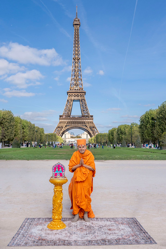 A Hindu guru in traditional orange robes performs a ritual in front of the Eiffel Tower, now closed amid outrage.