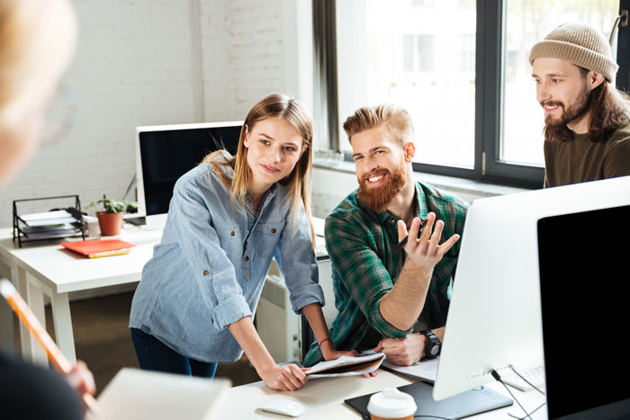Team discussing office space management policy at a computer