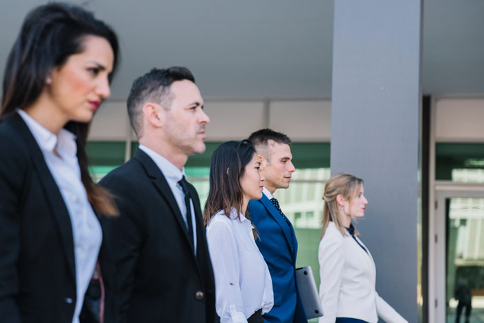 Group of business professionals walking in a line showing team area walking control concept