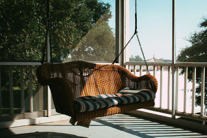 An empty wicker porch swing on a veranda, symbolizing a split and divorce.
