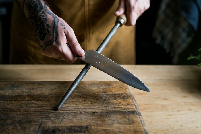 A person sharpening a chef knife on a steel rod during a divorce split dispute.