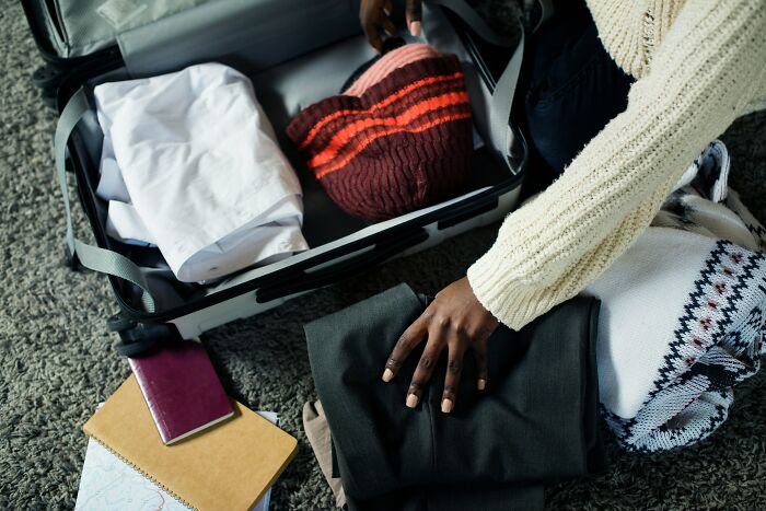 A person packing a suitcase on the floor, representing a split and moving out