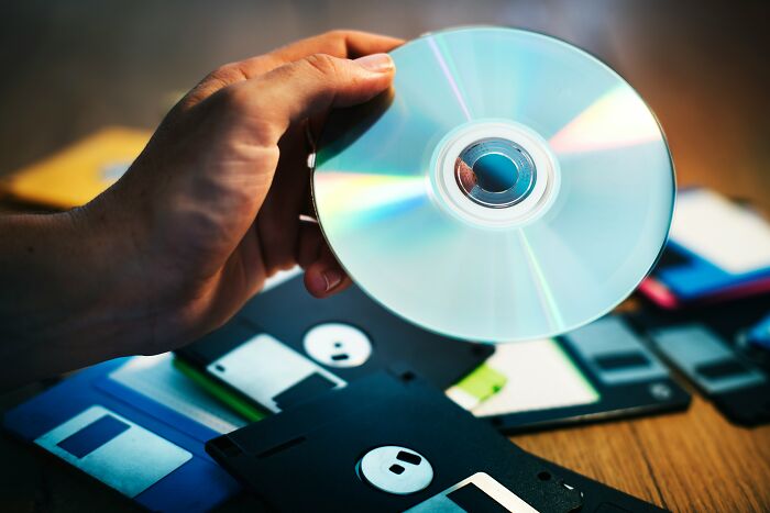 A hand holding a CD above a pile of floppy disks, highlighting property division during a split