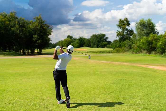 A man swinging a golf club on a green course, illustrating splitting assets in divorce