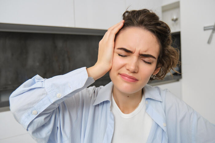 A woman holding her head, looking pained and upset, reflecting on a marriage that is over.