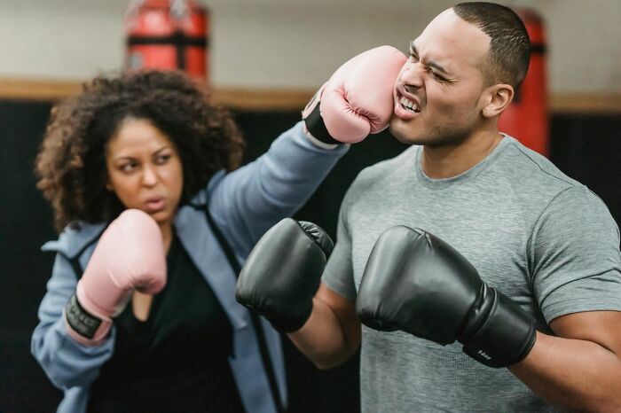 A woman punching a man in the face while boxing, representing a marriage ending due to conflict.
