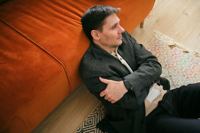 A man sitting on the floor, looking distraught, reflecting on his marriage being over.