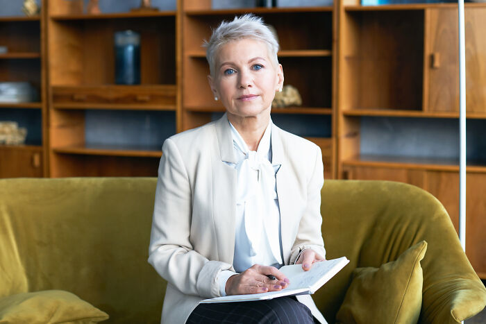A professional woman sitting on a couch with a notebook, reflecting on subtle sexism.