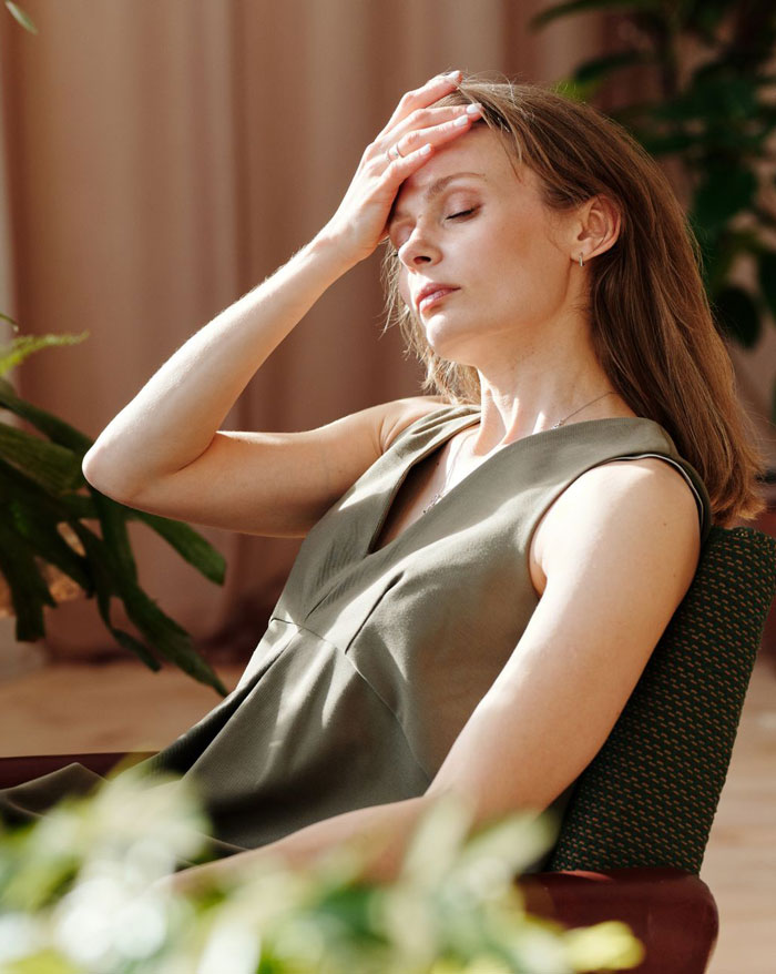 A stressed and exhausted woman sitting in a chair holding her forehead, upset about wedding guests drama. A stressed and exhausted woman sitting in a chair holding her forehead, upset about wedding guests drama.