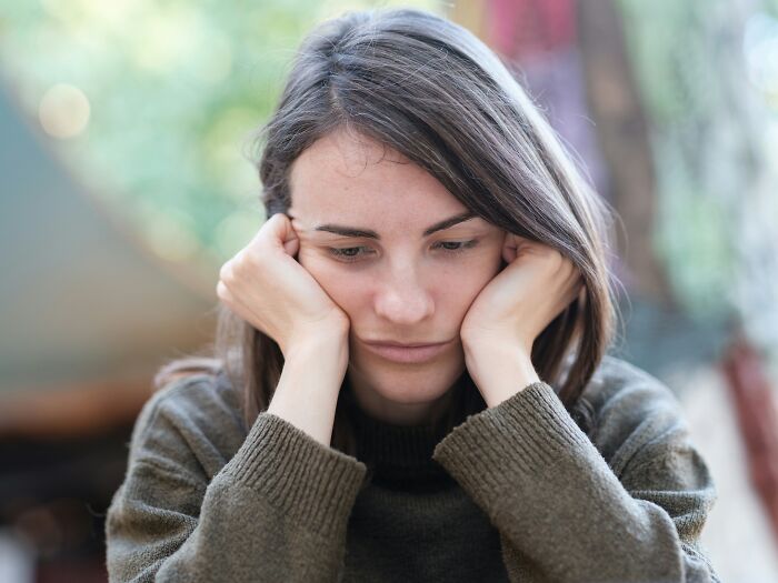 A sad woman with her head in her hands, reflecting on friends who are actually haters.