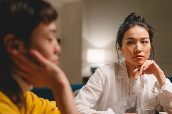 A woman looking intently at a friend, realizing that friends can sometimes be haters.