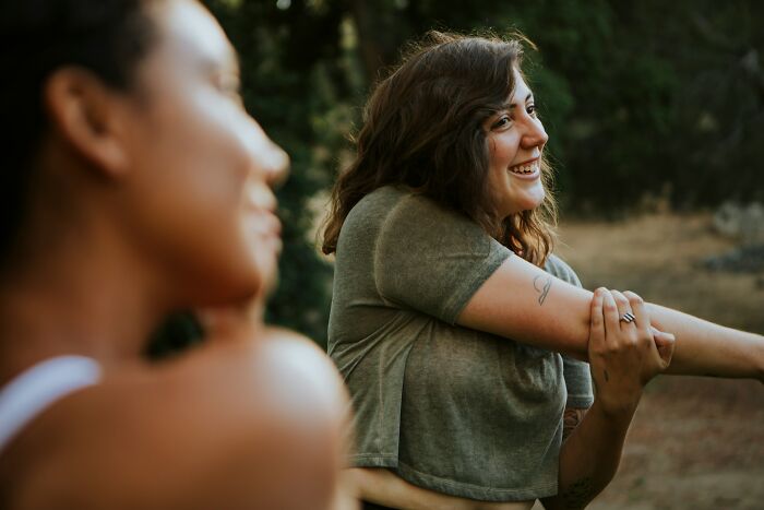 Two friends stretching outdoors, one smiling, despite the realization that friends can be haters.