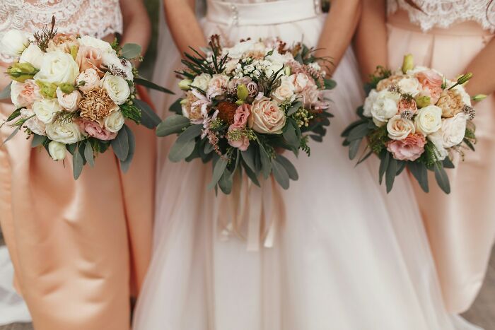 Three women, one in a wedding dress, holding bouquets; a reminder that friends can be haters.
