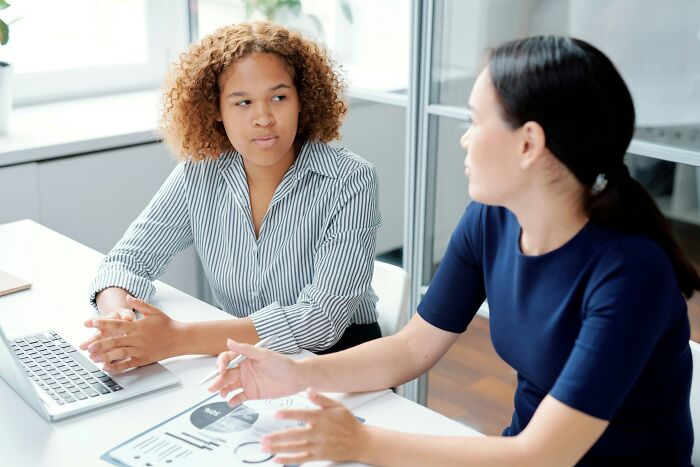 Two women discuss, one looking skeptical, as if realizing a friend is a hater.