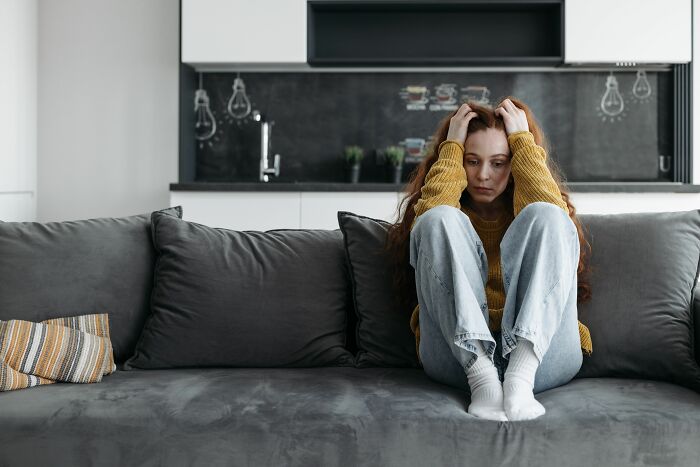 A distressed woman on a couch, troubled by secrets that came to light after people were gone.