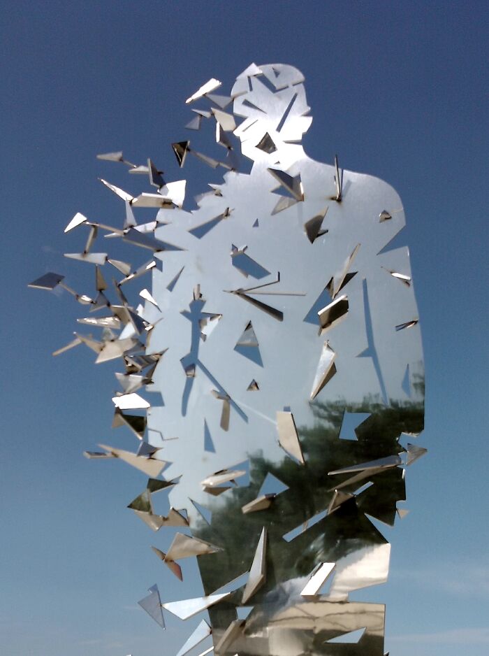 Close-up of reflective sculptures with scattered triangular pieces against a dark background