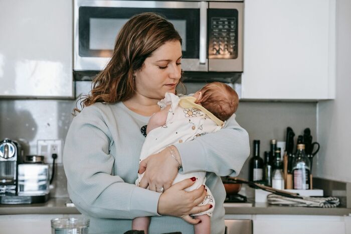 Mom holding baby in kitchen showing double duty with baby care