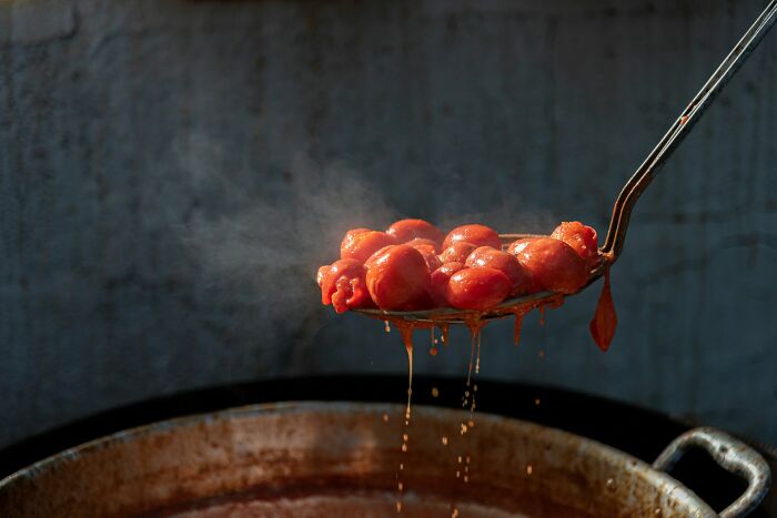 Metal ladle lifting steaming cooked tomatoes, illustrative of unusual diets in strange patients.