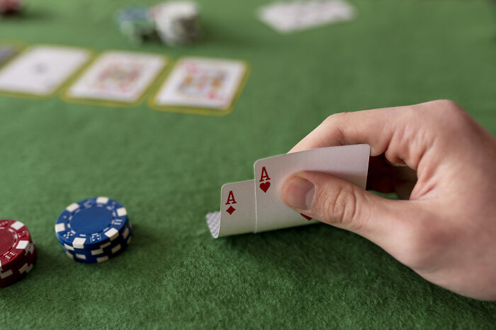 A poker player holding two aces on a green table, showing satisfying stories of letting a mistake speak for itself