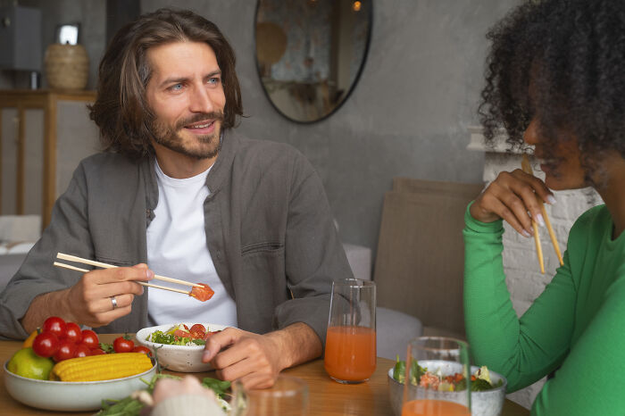 A man and a woman eating together, illustrating potential dating red flags during a meal.