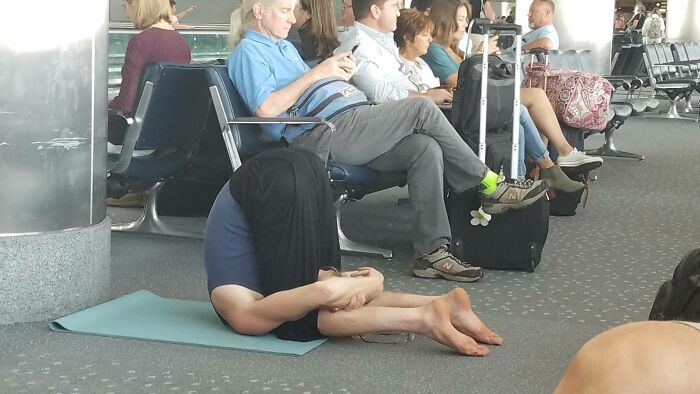 A person doing yoga on a mat in an airport, one of the weird things spotted at airports.
