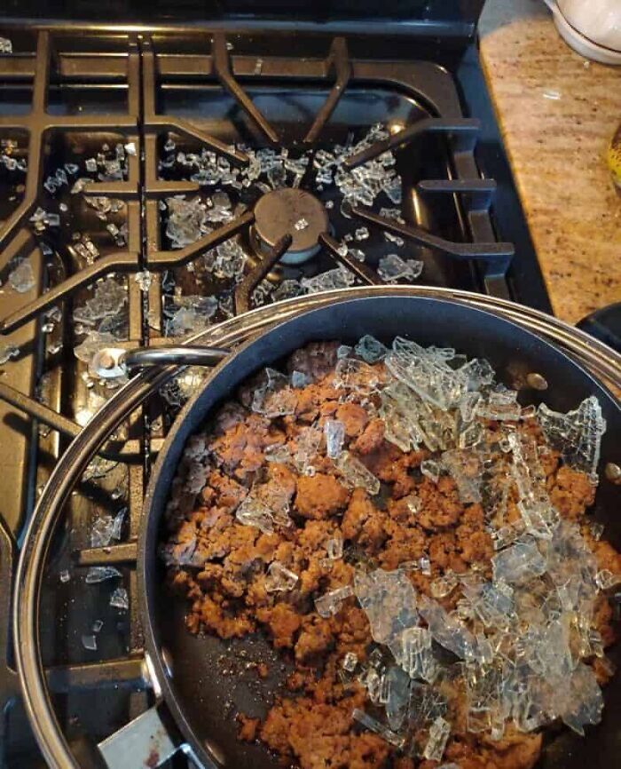 A severe kitchen fail with a stovetop covered in broken glass, and shards also mixed into a pan of cooked ground meat.