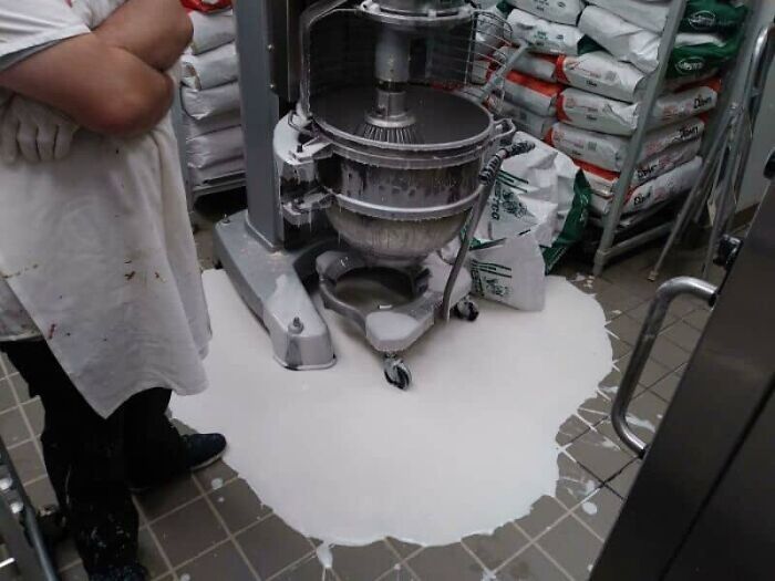 A large industrial mixer with spilled white batter all over the floor, a major kitchen fail.